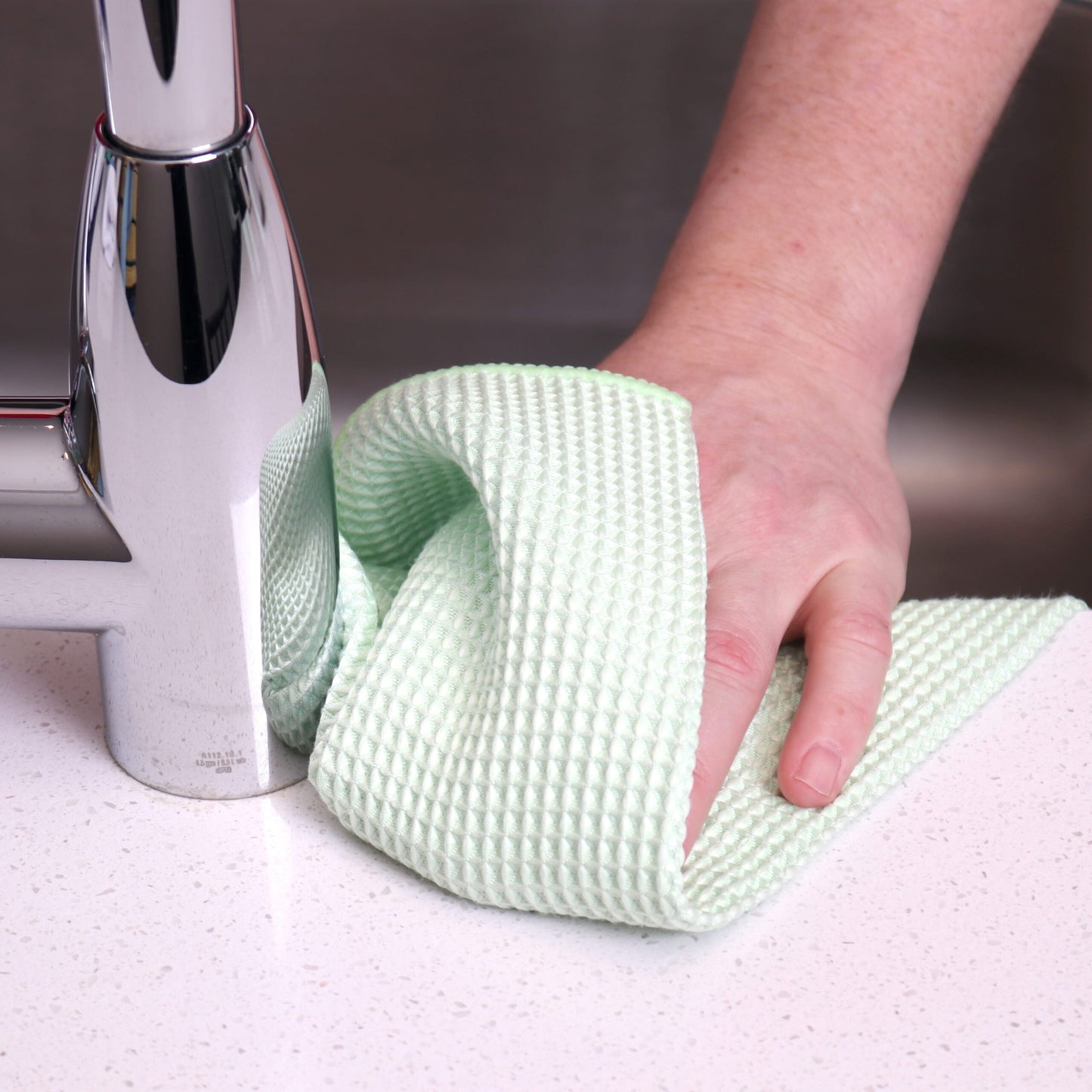 someone using a green waffle weave towel in the kitchen